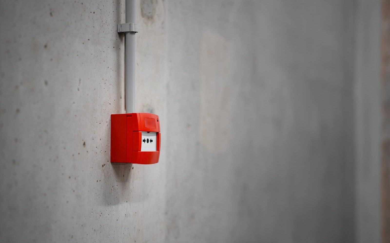 Wall-mounted alarm call point on a concrete wall